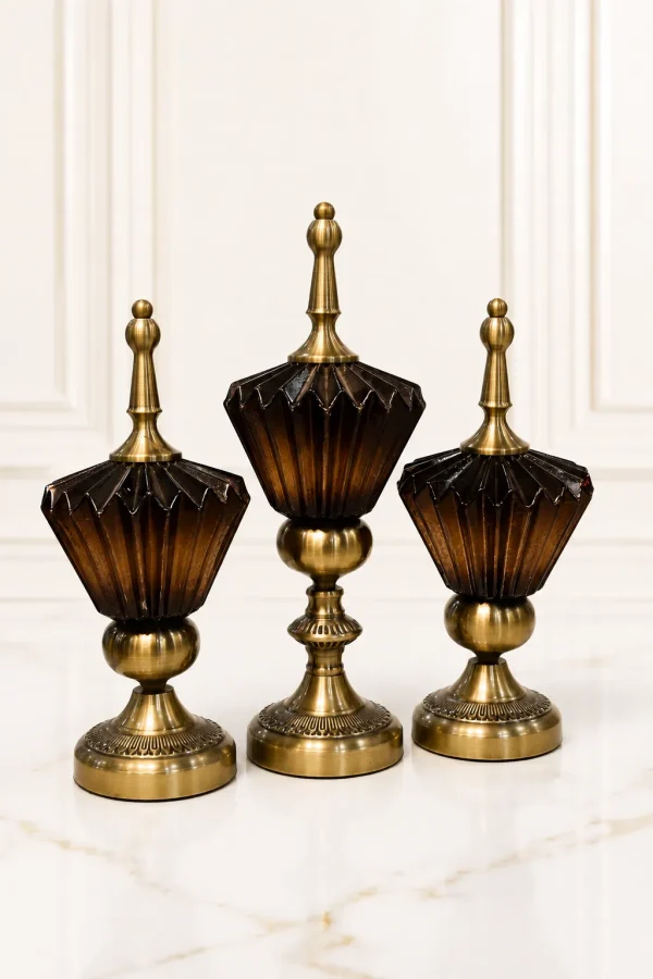 A set of three vintage-style decorative jars of varying heights featuring fluted dark brown glass containers mounted on antique brass pedestal bases with matching pointed brass finial lids, sitting on a speckled marble tabletop