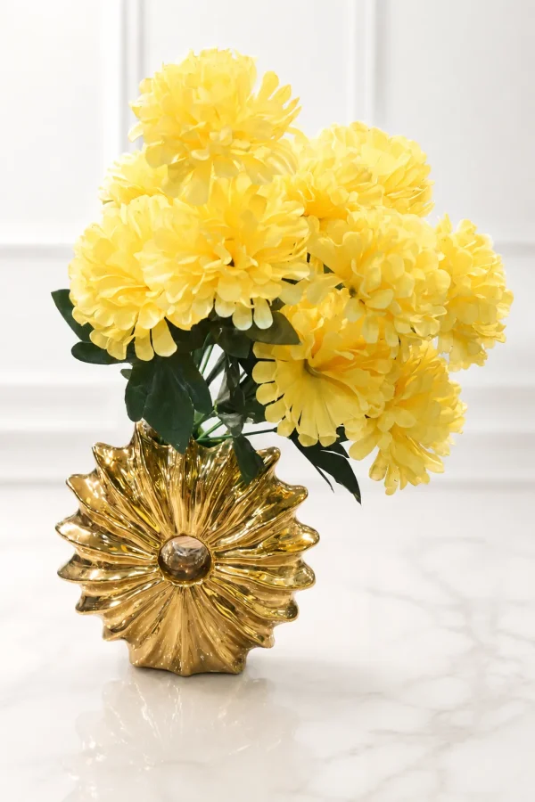 Luxury gold ceramic sunburst vase with a vibrant yellow artificial flower bouquet displayed on a wooden table.