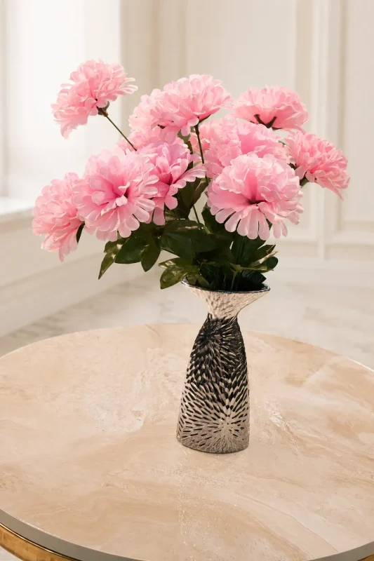 Textured silver vase filled with pink flowers on a marble table