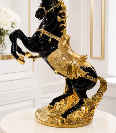 Luxury black and gold rearing horse resin statue with intricate gold detailing displayed on a round marble-top table.