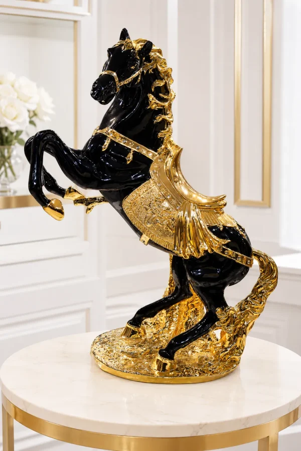 Luxury black and gold rearing horse resin statue with intricate gold detailing displayed on a round marble-top table.