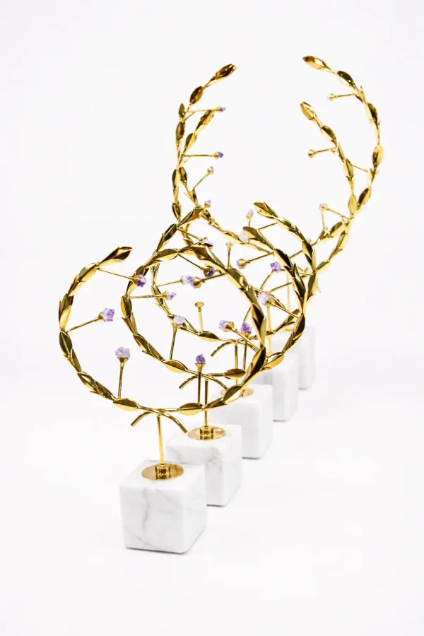Luxury gold abstract leaf sculpture with crystal-like accents on a white marble base displayed on a tabletop.