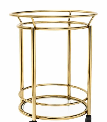 Modern round gold bar cart featuring a two-tier cylindrical frame with clear glass shelves and black rolling caster wheels on a solid white background.