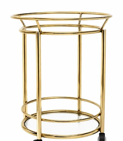 Modern round gold bar cart featuring a two-tier cylindrical frame with clear glass shelves and black rolling caster wheels on a solid white background.