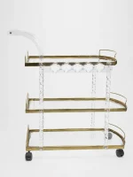 Premium clear acrylic and gold 3-tier bar cart featuring twisted lucite support pillars, transparent glass shelves, an integrated curved handle, and rolling caster wheels over a solid white backdrop.