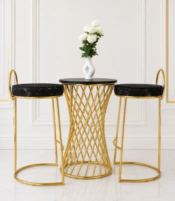 Luxury 3-piece bar bistro set featuring a round black table with a gold woven hourglass base, flanked by two gold bar stools with round black marble-patterned velvet cushions, set against a white paneled wall.