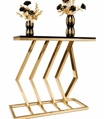 A luxury rectangular console table with a polished gold metal base featuring an abstract parallel chevron and diamond design, topped with a smooth black surface displaying two black and gold decorative vases.