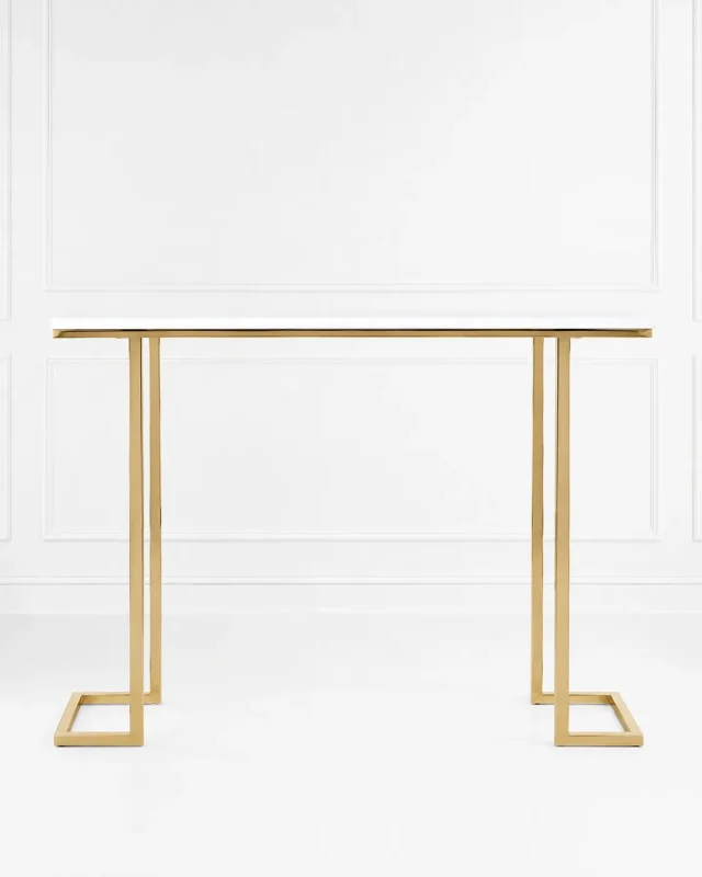 Modern gold console table with a minimalist white top and geometric metal frame legs, set against a clean white wall paneling backdrop.