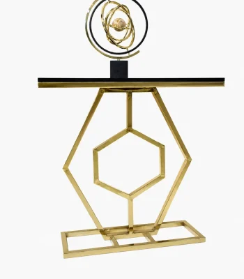 A luxury modern console table featuring a polished gold geometric hexagon metal frame, a sleek black tabletop, and a gold decorative armillary sphere on top, isolated against a white background.