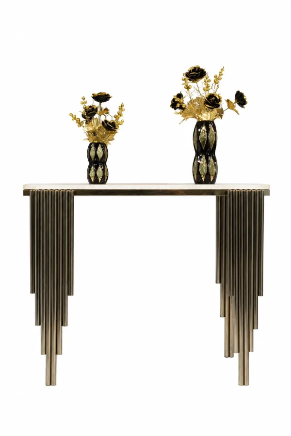 A modern luxury console table with a polished white marble top and a unique pedestal base made from clustered, stepped vertical metal pipes, styled with two black and gold decorative vases against a solid white background.
