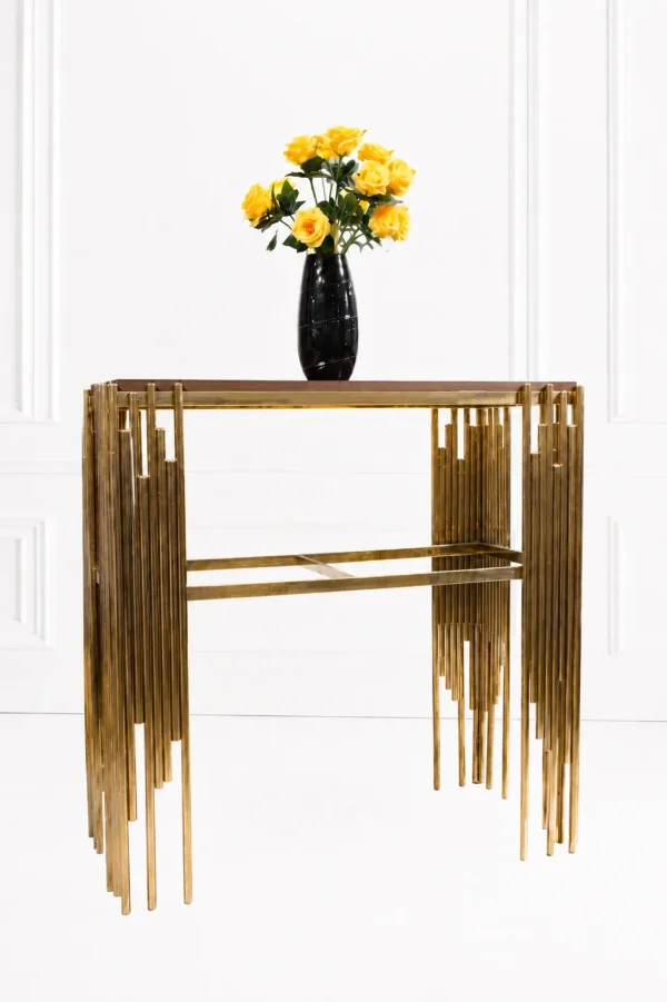 Luxury modern console table featuring a dark wood top and side pillars made of staggered, polished gold vertical metal rods, shown with a flower vase.