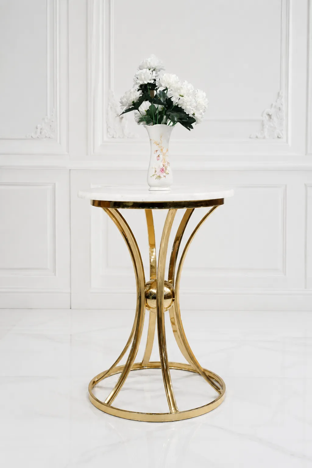 Luxury Round Marble Top Side Table – Modern Hourglass Gold Base End Table for Living Room Modern round side table with a polished white marble top and a decorative hourglass-shaped gold metal frame base, holding a white flower vase against a classic paneled wall.