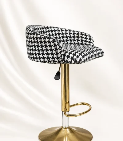 Modern houndstooth gold bar stool from with a black and white patterned swivel cushion seat and a polished metallic gold pedestal base.