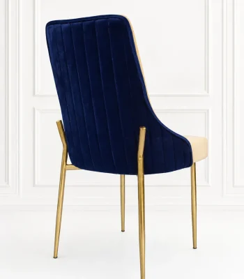 Blue velvet accent chair from showing the back view with vertical channel tufting and a two-tone frame on polished gold metal legs.