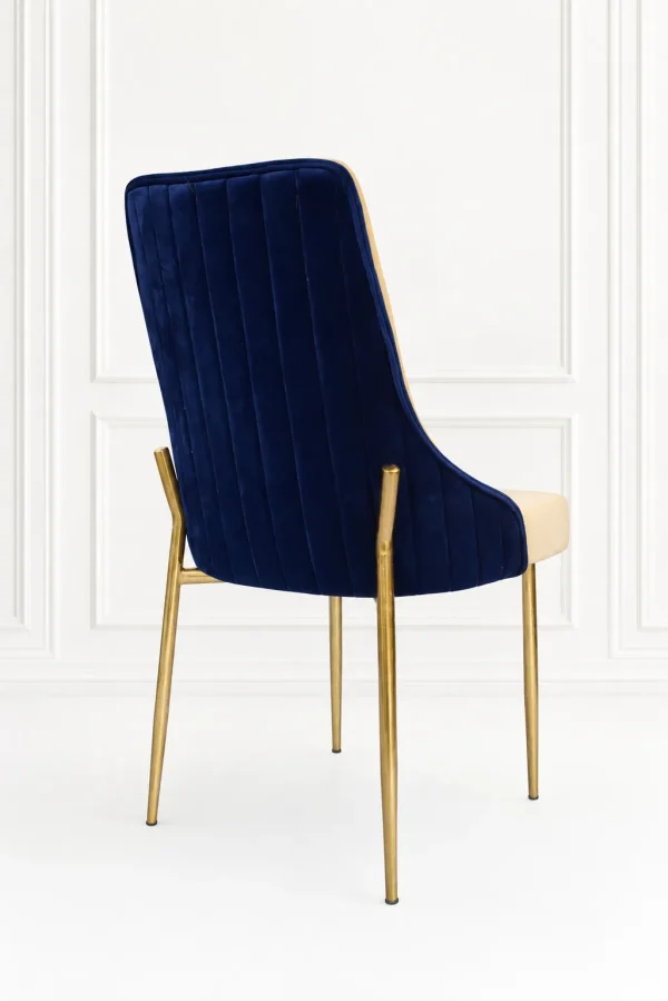 Blue velvet accent chair from showing the back view with vertical channel tufting and a two-tone frame on polished gold metal legs.