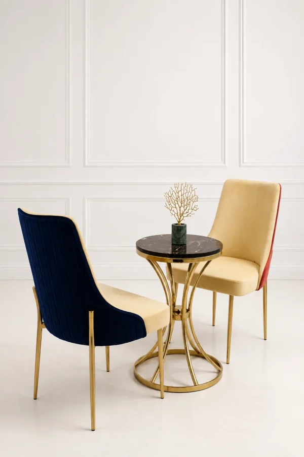 Luxury velvet dining chairs with round black marble top gold metal bistro table in a modern dining room.