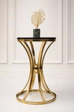 Luxury modern round side table featuring a polished black marble top and a decorative hourglass-shaped gold metal pedestal base, holding a gold coral sculpture.