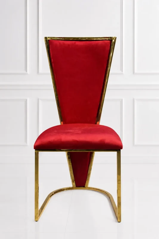 Luxury high-back dining chair featuring royal red velvet upholstery and a polished gold metallic trim frame against a white paneled wall background.
