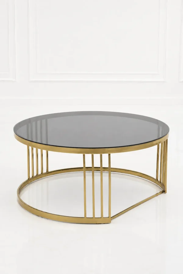 Modern round coffee table featuring a clear dark smoked glass top and an open-back crescent base with polished gold vertical accent bars against a white background.