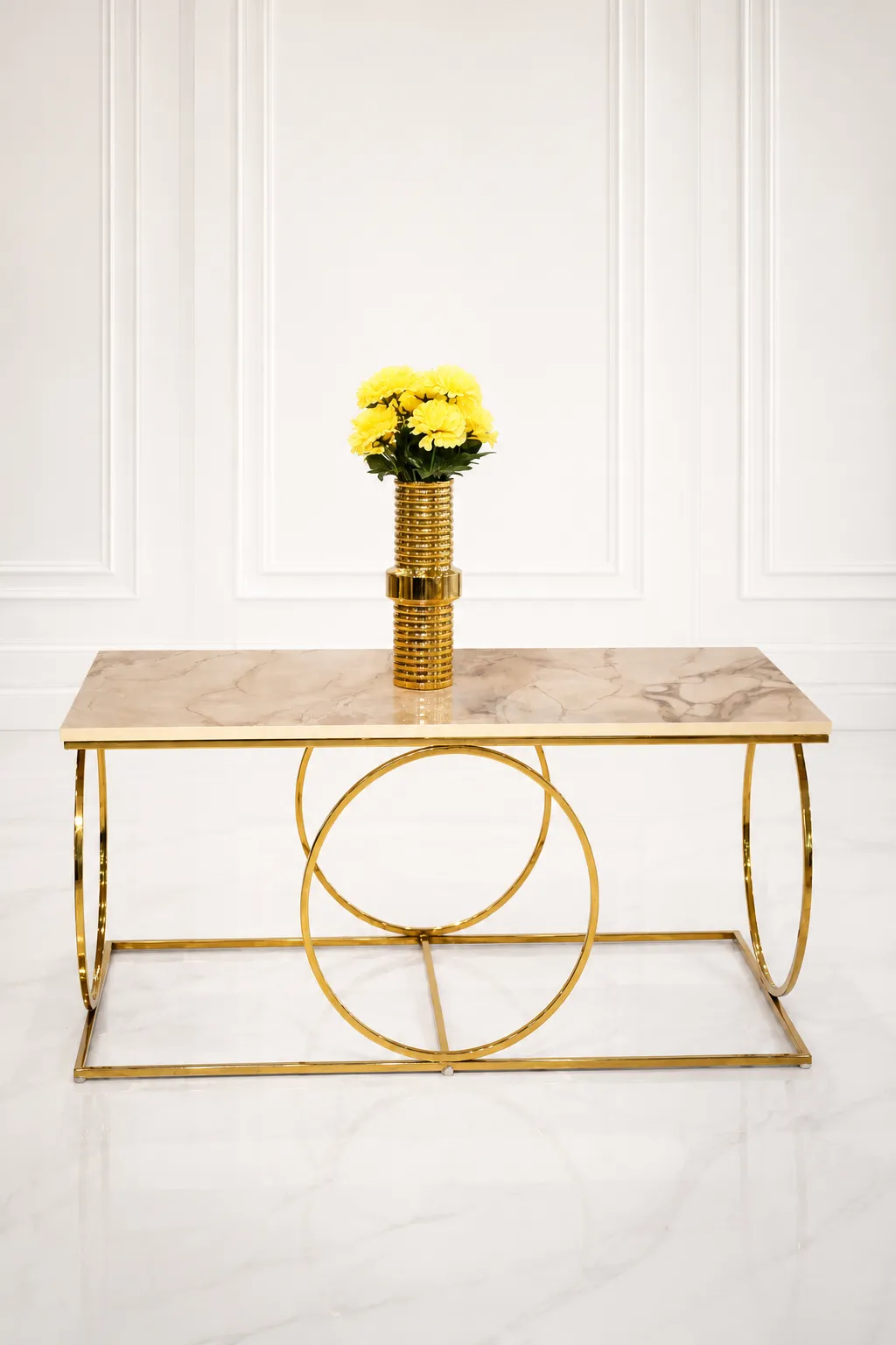 Luxury Rectangular Marble Coffee Table – Modern Geometric Gold Interlocking Ring Base Center Table Luxury modern rectangular coffee table featuring a polished beige marble top and a geometric base made of interlocking polished gold metal rings, styled with a gold flower vase.