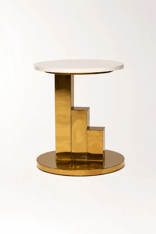 Modern gold side table with a sleek round white tabletop and a high-shine polished brass stepped pedestal base, isolated against a clean white background.