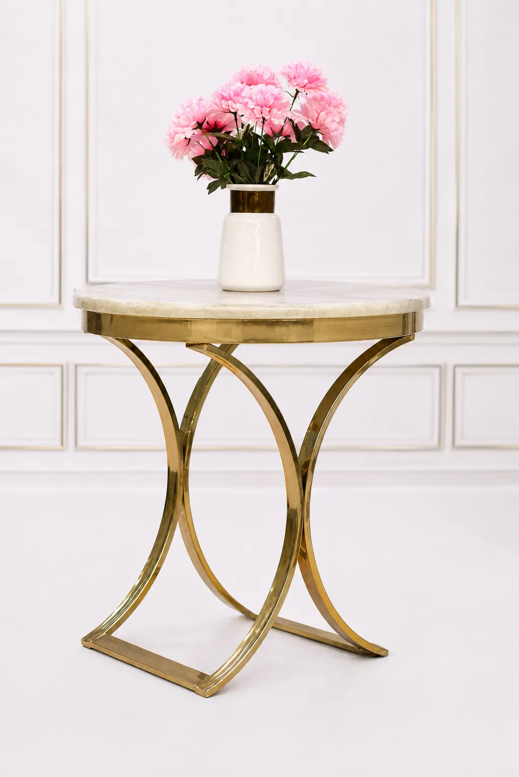 Modern Round Cream Marble Side Table with Sculptural Gold Crescent Base Round cream marble side table with a polished gold crescent-shaped metal base, displaying a white ceramic vase with pink flowers against a white wall molding background