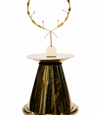 Round black marble side table with a polished dark stone top and a modern architectural multi-pillar gold metal base, isolated against a white background.