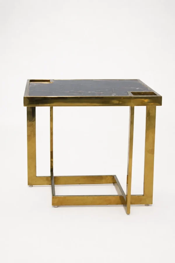 Square black marble side table featuring a thick polished gold metal frame and an interlocking open cubic base, isolated against a solid white background.