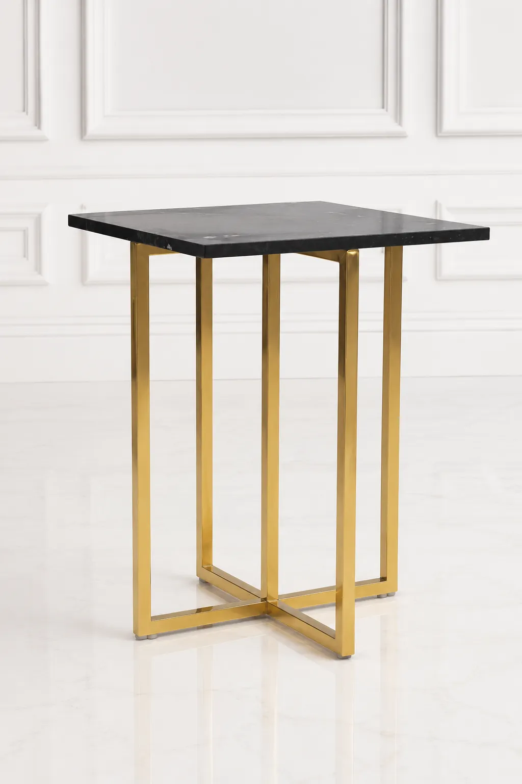 Modern Square Black Marble Side Table with Tall Gold Cross-Base Frame Tall square black marble side table with an architectural polished gold metal cross-base frame, positioned against a classic white wall panel background.
