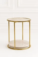 Modern round marble side table with gold frame displayed against a clean, white minimalist paneled wall backdrop in file