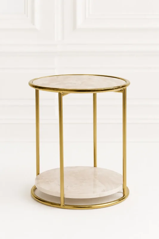 Modern round marble side table with gold frame displayed against a clean, white minimalist paneled wall backdrop in file