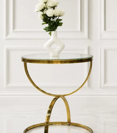 Luxury round glass top side table with gold crescent base featuring a white vase of roses