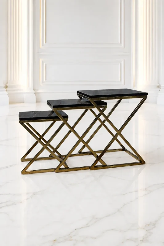 Set of three luxury rectangular black marble nesting tables with gold x base arranged in a tiered, staggered layout