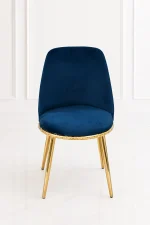 Luxury navy blue velvet dining chair with an ergonomic backrest, featuring a textured gold base rim and polished gold legs, set against a clean white paneled wall.