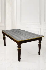 Rectangular luxury dark wood dining table featuring a grey textured wood-grain top, polished gold edge trim, and sculpted glossy dark legs with gold accent rings.