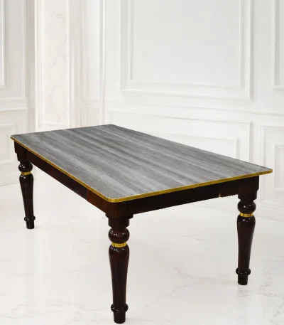 Rectangular luxury dark wood dining table featuring a grey textured wood-grain top, polished gold edge trim, and sculpted glossy dark legs with gold accent rings.