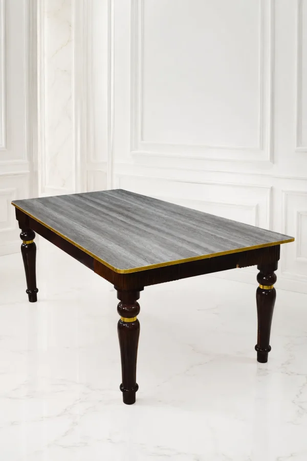 Rectangular luxury dark wood dining table featuring a grey textured wood-grain top, polished gold edge trim, and sculpted glossy dark legs with gold accent rings.