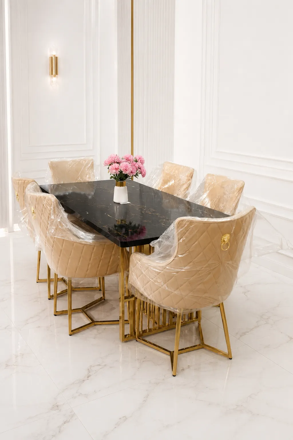 Aurelia 6-Seater Luxury Dining Set – Black Marble Top with Gold Stainless Steel Legs and Tufted Velvet Chairs A luxury 6-seater dining set featuring a rectangular black marble tabletop with gold stainless steel legs, styled with six beige tufted velvet chairs under protective plastic wrapping in a bright, modern white dining room.