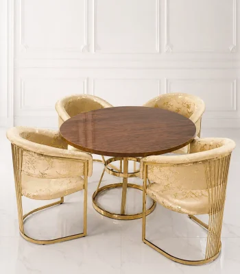 A luxury 4-seater round dining set featuring a high-gloss walnut wood top and geometric gold stainless steel base, styled with four cream and gold patterned barrel chairs against a clean, white paneled wall background.