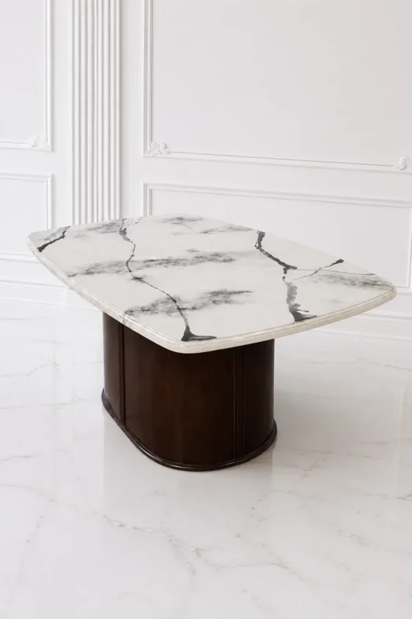 Rectangular white marble dining table with bold black veining and rounded corners, anchored by a solid dark wood oval pedestal base in a white room.