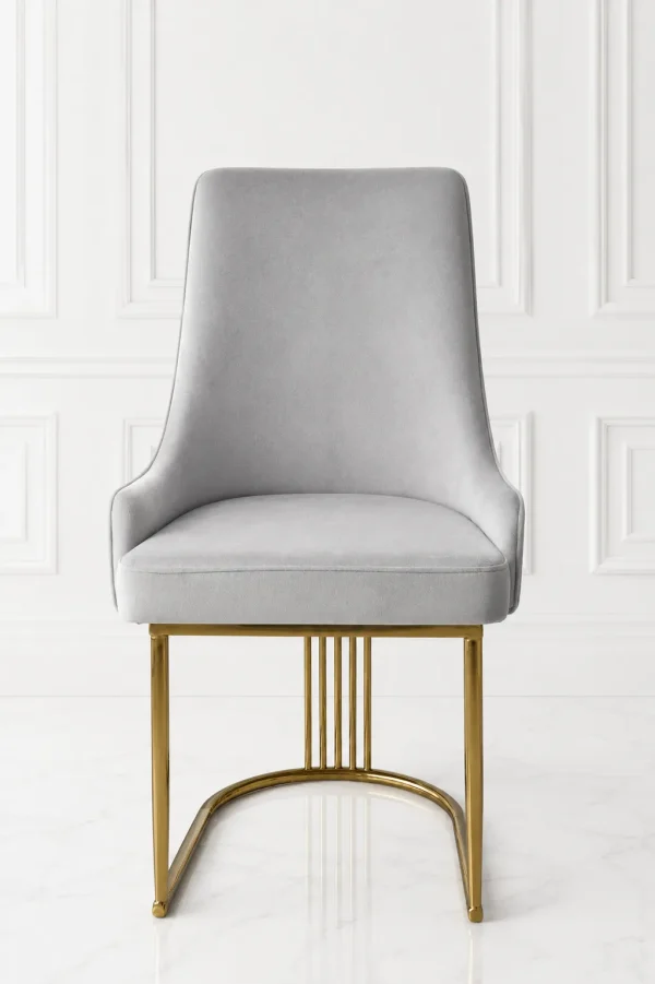 Front view of a luxury high-back light grey velvet dining chair supported by a polished gold stainless steel curved base with vertical slatted accents, against a white wall.