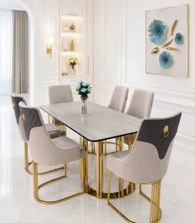 A luxury 6-seater dining set featuring a grey rectangular sintered stone tabletop on polished gold pillar legs, styled with six two-tone grey velvet chairs featuring diamond tufting and gold lion-head pulls in a bright, modern white dining room.