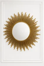 Luxury gold sunburst wall mirror with a multi-layered starburst stainless steel frame centered on a white paneled wall.