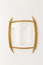 Luxury asymmetric gold wall mirror with an abstract barrel shape and staggered stainless steel side rods mounted on a textured white wall.