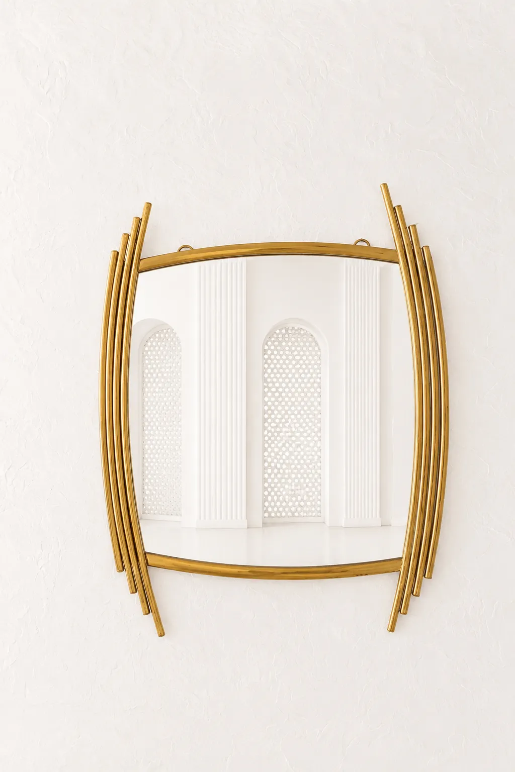 Luxury Asymmetric Gold Wall Mirror – Abstract Stainless Steel Barrel Accent Mirror Luxury asymmetric gold wall mirror with an abstract barrel shape and staggered stainless steel side rods mounted on a textured white wall.