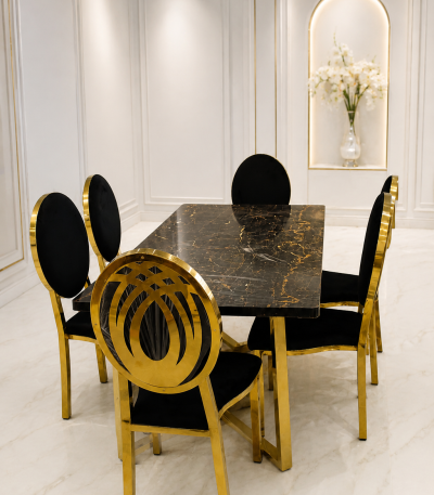 A luxury dining room set featuring a rectangular black marble table with gold veining and black velvet chairs with gold-finished circular metal frames.