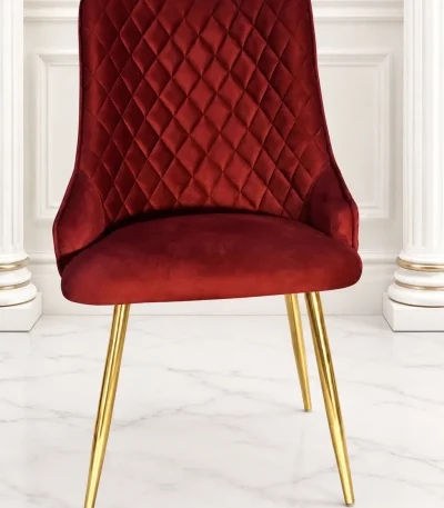 Luxury burgundy velvet dining chair with quilted back and gold metal legs.