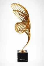 Abstract gold metal wire ribbon sculpture on a square black marble base
