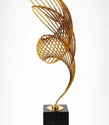 Abstract gold metal wire ribbon sculpture on a square black marble base
