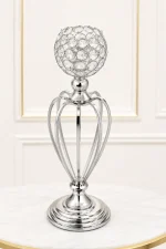 Elegant silver crystal goblet candle holder featuring an open hollow-cage metallic stem and a tiered circular base on a marble table surface.